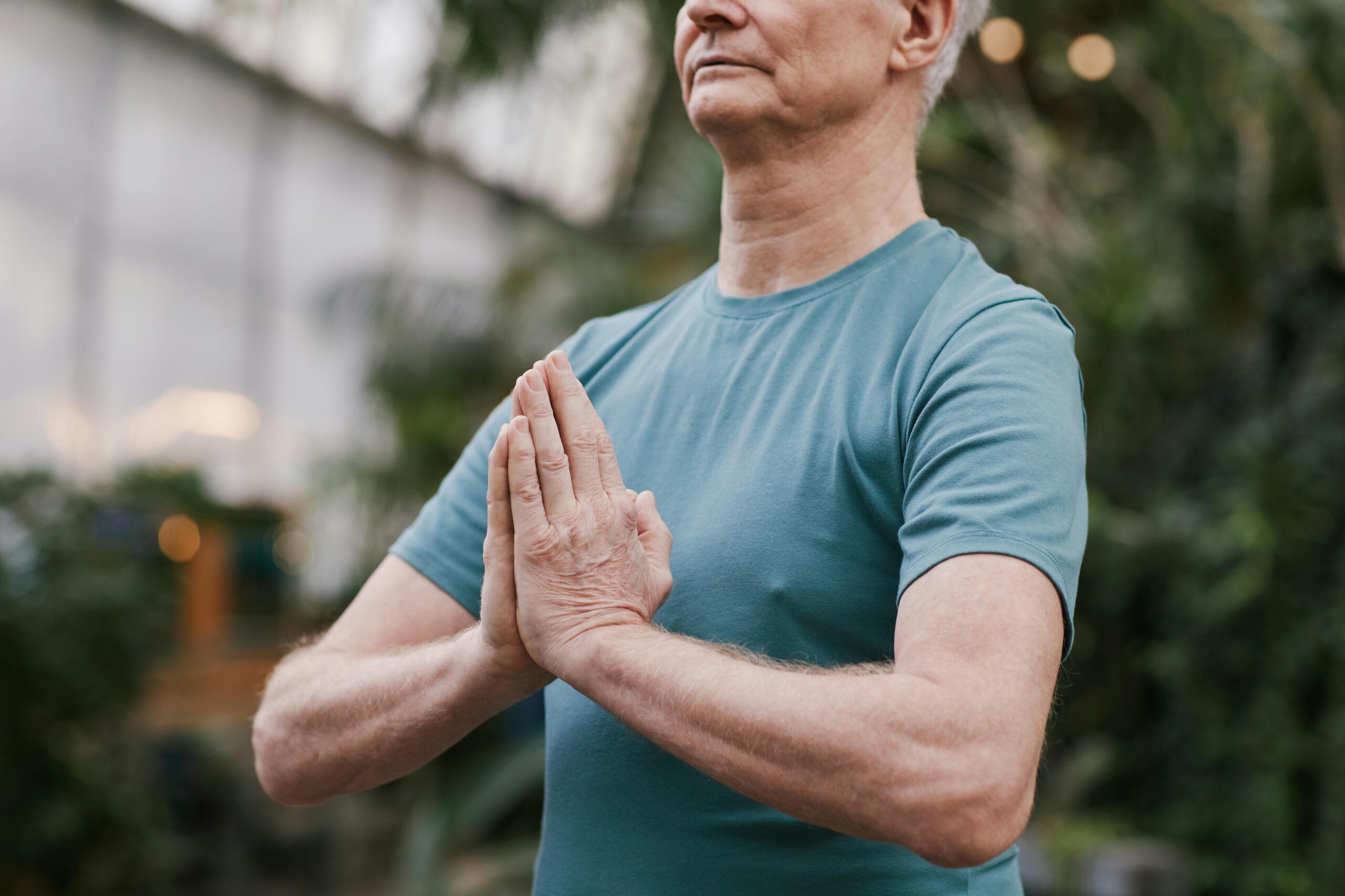 Hombre mayor practicando yoga en interiores, simbolizando bienestar y salud en adultos mayores.