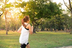 Mujer corriendo al amanecer en un parque, simbolizando actividad física y bienestar en adultos.