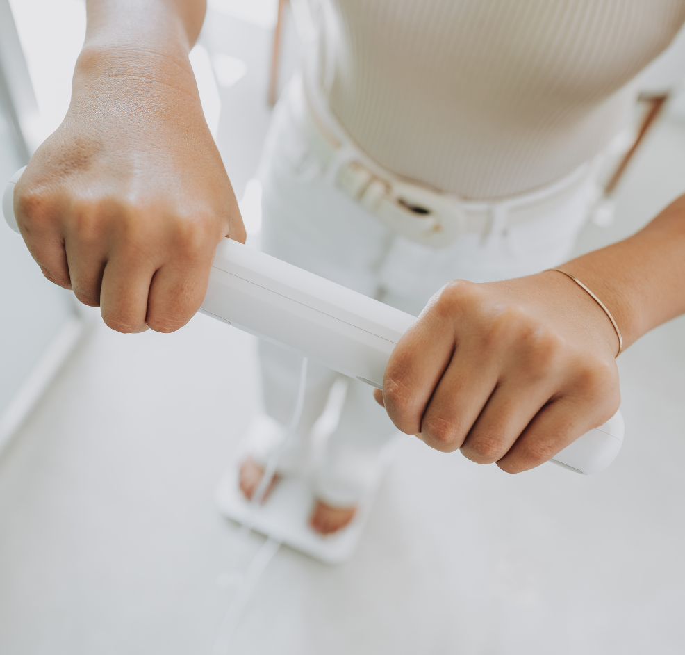 Persona realizándose una valoración corporal encima de una báscula de bioimpedancia