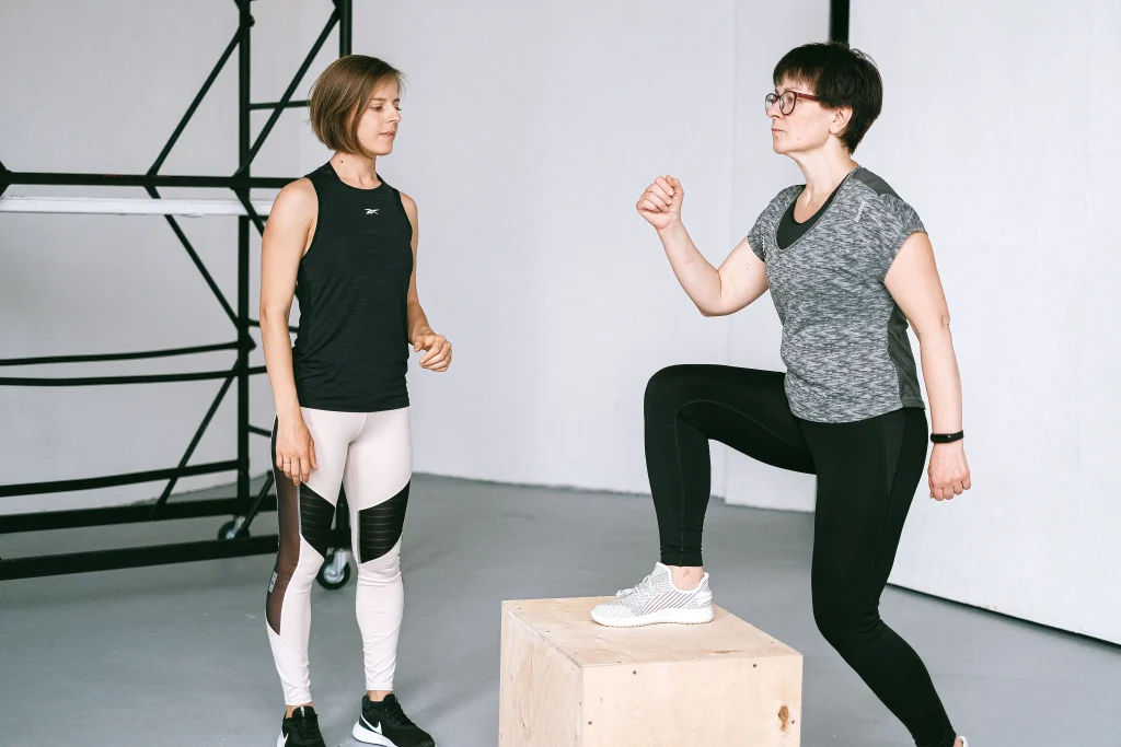 Entrenadora con una mujer adulta joven que esta subiendo hacia un cajon