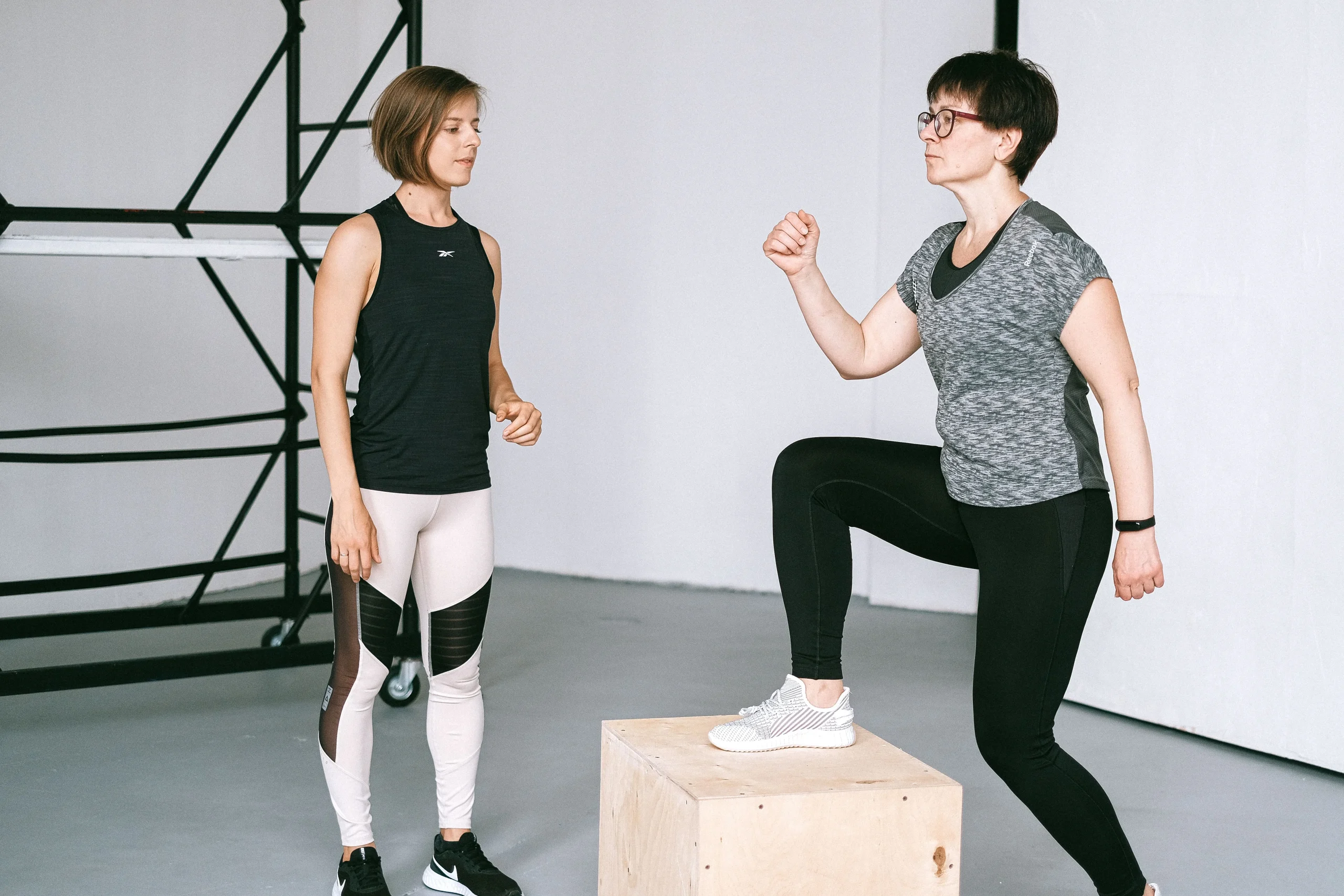 Entrenadora con una mujer adulta joven que esta subiendo hacia un cajon